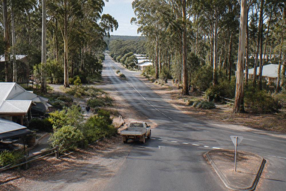 A signposted rural highway junction with tree plantations on both sides